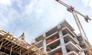 Budowa budynku z dźwigiem i pracownikiem w żółtym kasku. BIM w akcji, tworzy przyszłość.