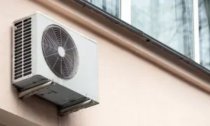Jednostka zewnętrzna klimatyzatora zamontowana na ścianie bloku.