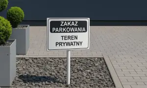 Znak "Zakaz parkowania - teren prywatny" na tle nowoczesnego budynku i zieleni.