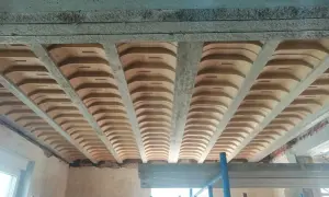 Widok od dołu na strop gęstożebrowy z betonowymi belkami i pustakami ceramicznymi.