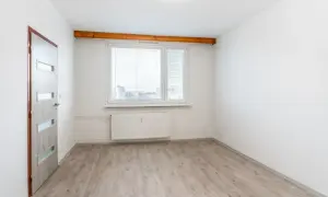 Puste pomieszczenie z drzwiami i oknem, gotowe do zamieszkania. To może być pierwsze mieszkanie komunalne.