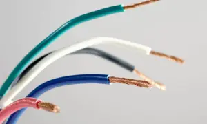 Sześć przewodów elektrycznych w różnych kolorach: zielonym, białym, czarnym, niebieskim i różowym, z odsłoniętymi miedzianymi żyłami. Różnorodność kolorów faz ułatwia identyfikację.