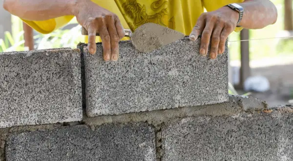 Budowniczy układa bloczki betonowe fundamentowe, tworząc solidną podstawę.