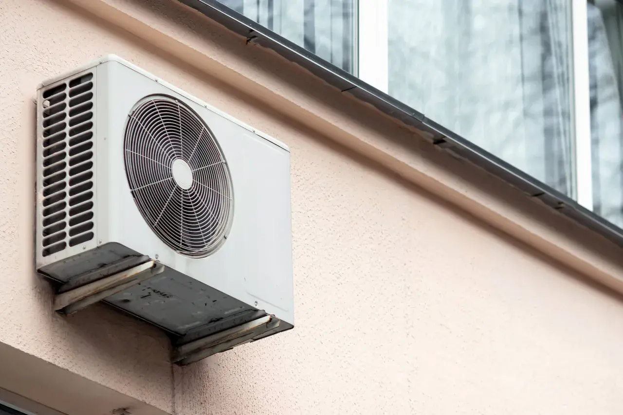 Jednostka zewnętrzna klimatyzatora zamontowana na ścianie bloku.