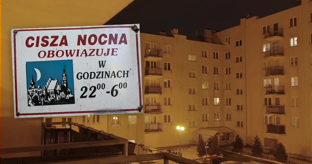 Tabliczka informuje o ciszy nocnej obowiązującej od 22:00 do 6:00. W tle widać blok mieszkalny nocą.