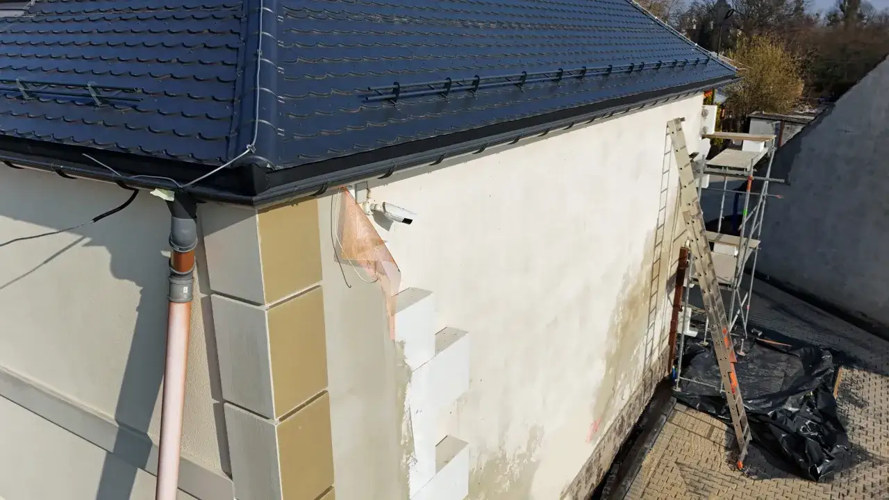 Dom w trakcie ocieplania. Widać rusztowanie, styropian i kamery. Sprawdź, jaka jest cena ocieplenia za 1m2 robocizna.