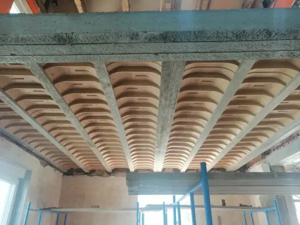 Widok od dołu na strop gęstożebrowy z betonowymi belkami i pustakami ceramicznymi.