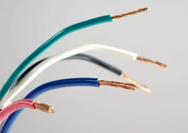 Sześć przewodów elektrycznych w różnych kolorach: zielonym, białym, czarnym, niebieskim i różowym, z odsłoniętymi miedzianymi żyłami. Różnorodność kolorów faz ułatwia identyfikację.